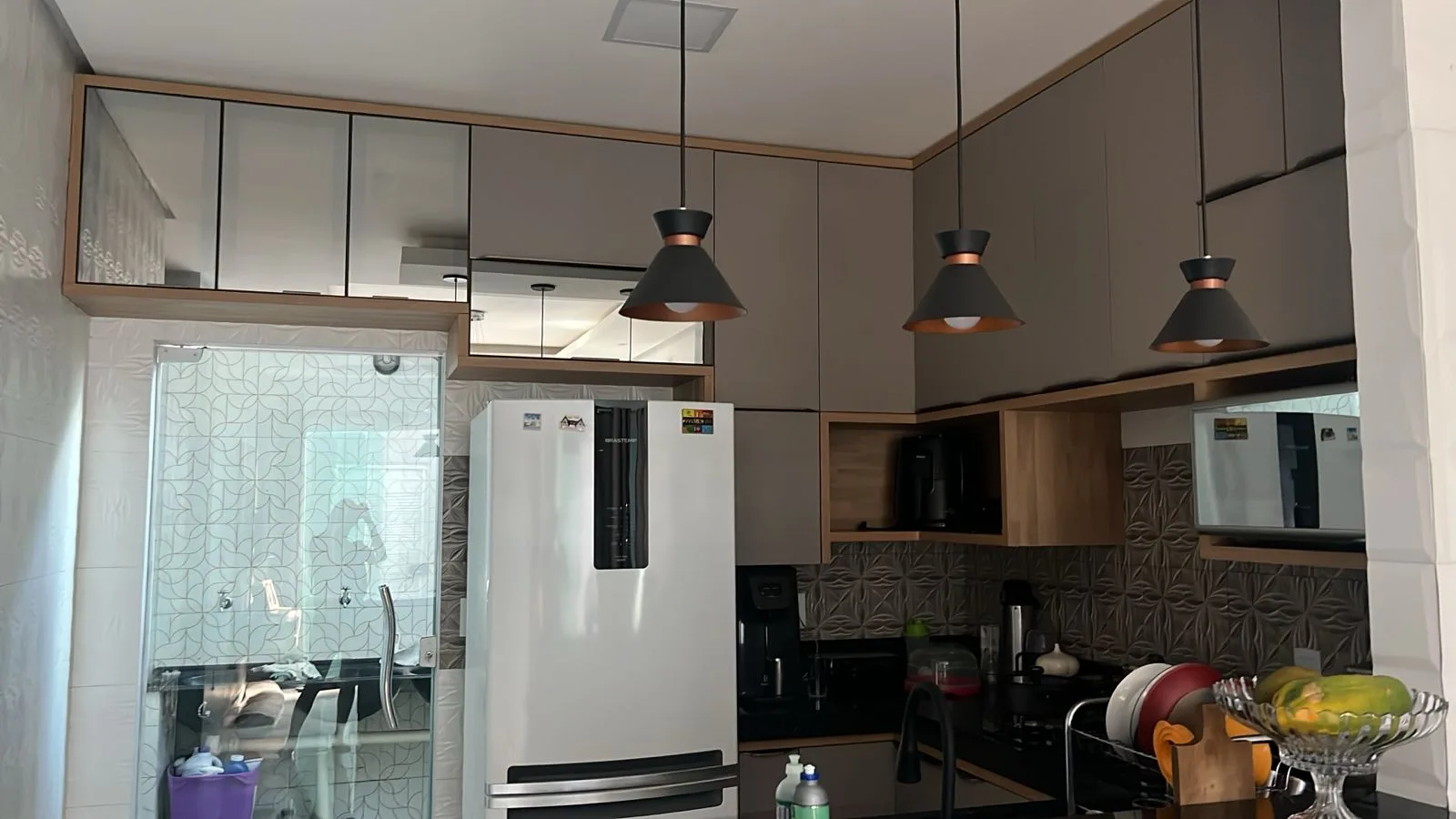 Cozinha planejada em tom fendi com detalhes amadeirados e pendentes