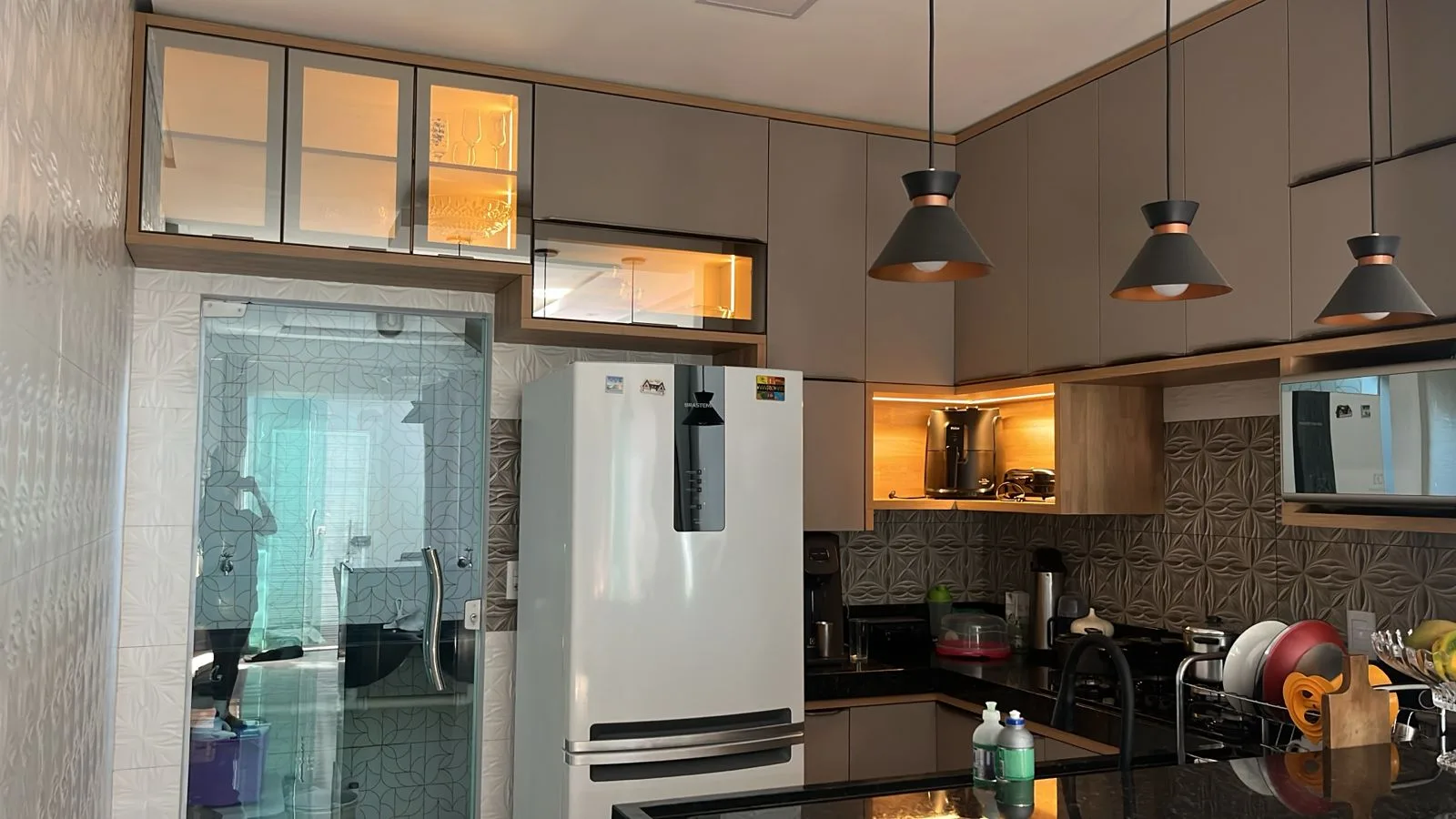 Cozinha planejada com iluminação em LED nos nichos e portas de vidro