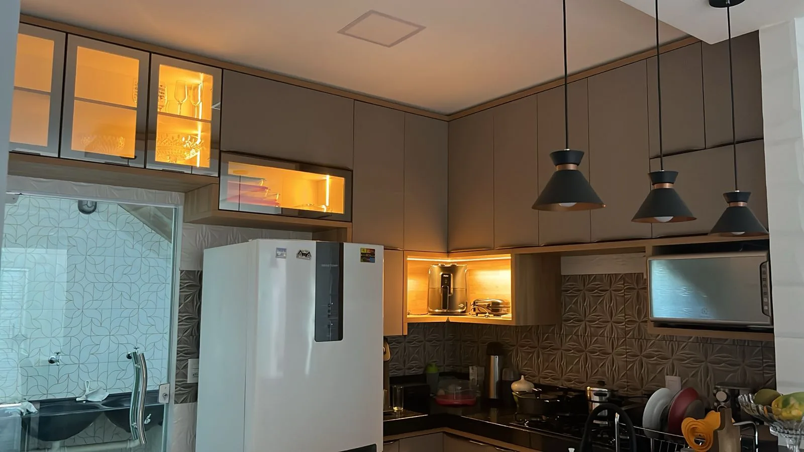 Cozinha planejada iluminada com cristaleira e armários até o teto
